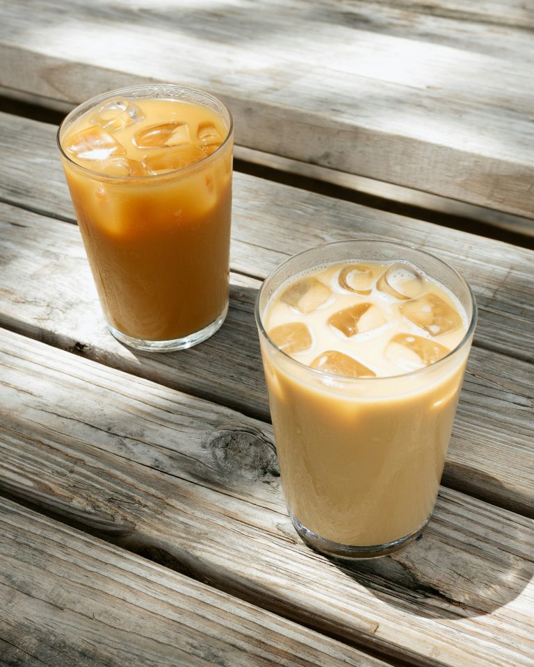 two glasses of cold brew coffee sitting on a wooden table