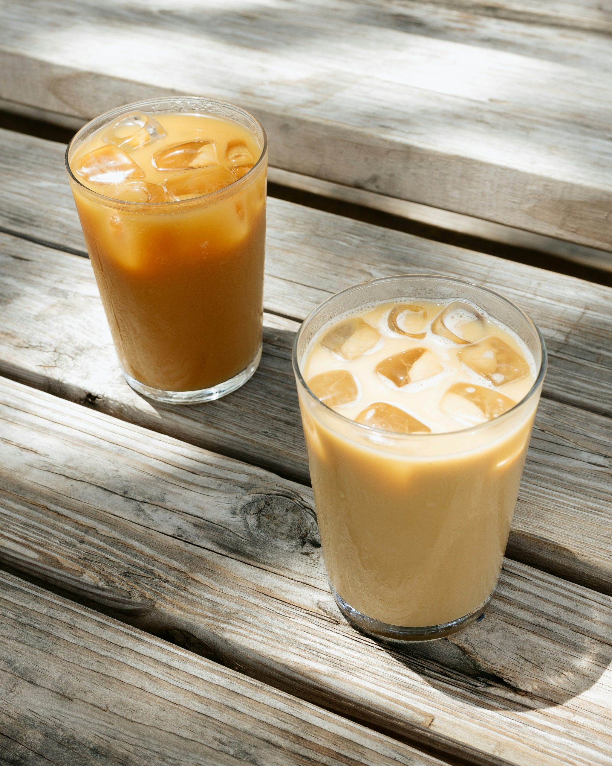 two glasses of cold brew coffee sitting on a wooden table
